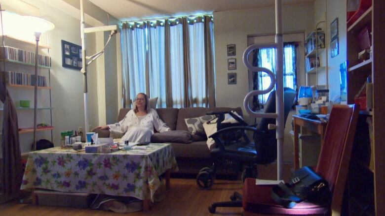 A woman sits on a couch in a living room.