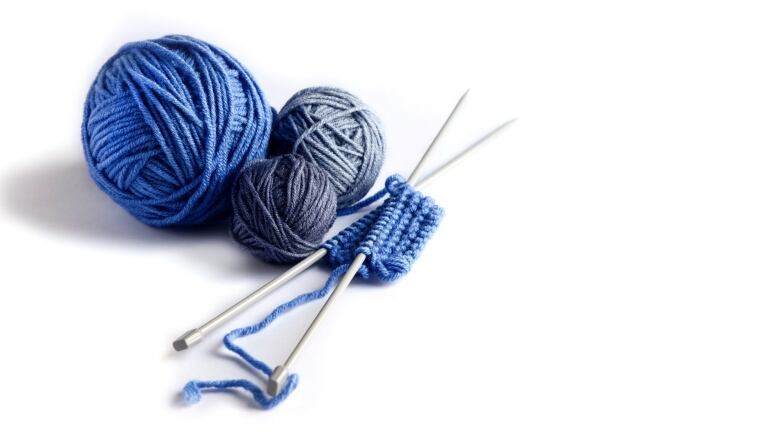 Blue knitted wool on a white background with knitting needles for knitting warm clothes.