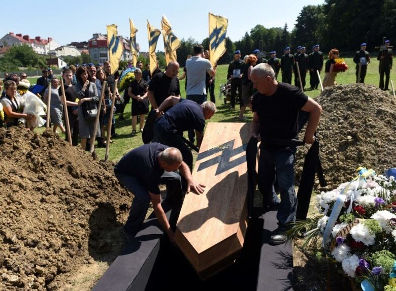 A coffin is lowered into the ground.