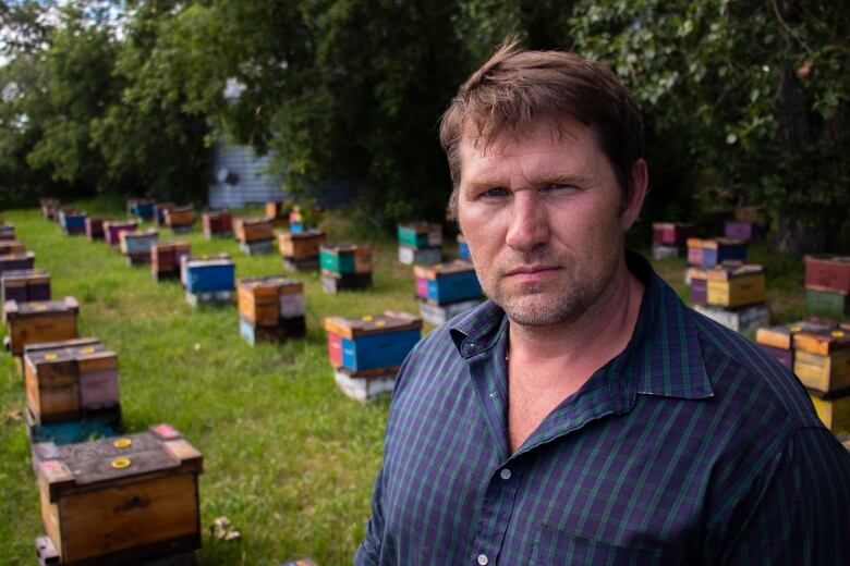 Person in collared plaid shirt in front of rows of boxes on the ground.