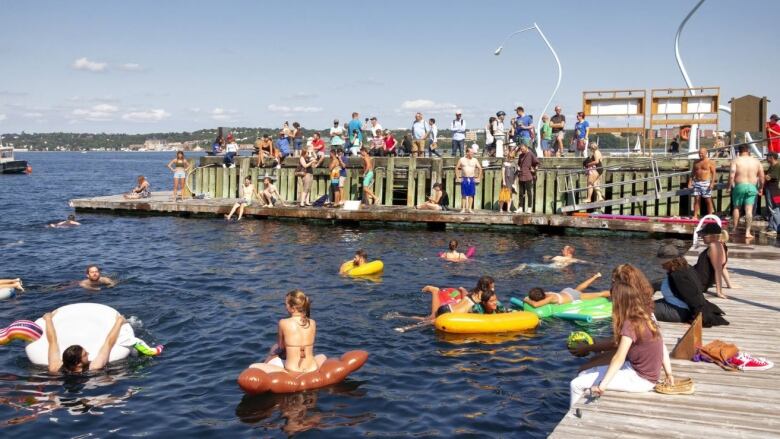 People swim and play on inflatable rafts in Halifax harbour