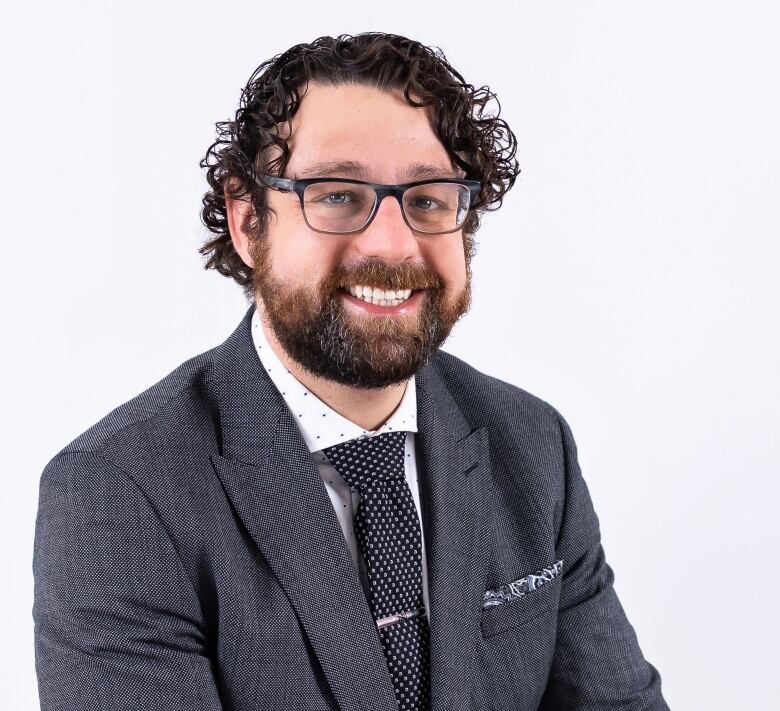 A smiling man wearing a suit jacket.