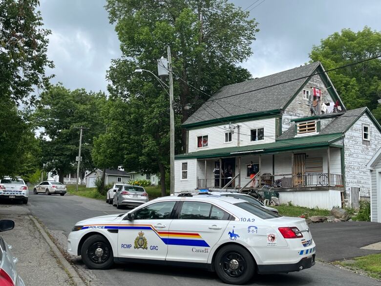 Several RCMP cars parked outside a large, delapitated apartment building.