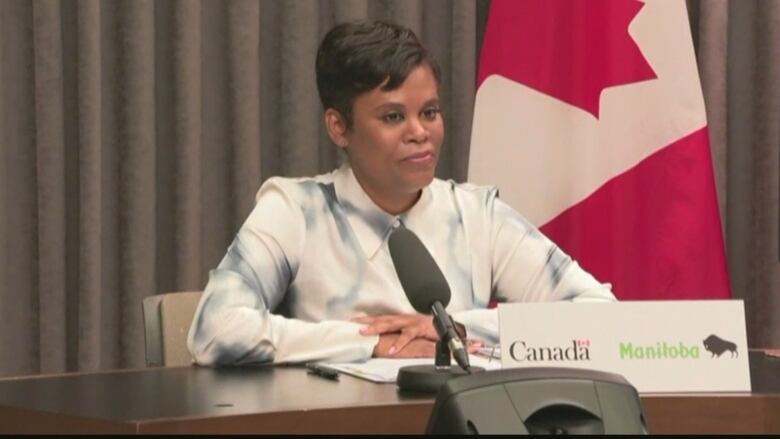 A woman with short hair sits in front of a microphone.