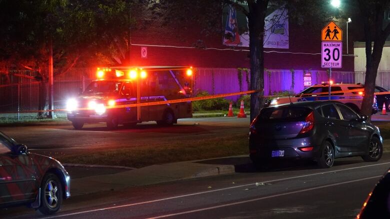 An ambulance with lights flashing behind police tape