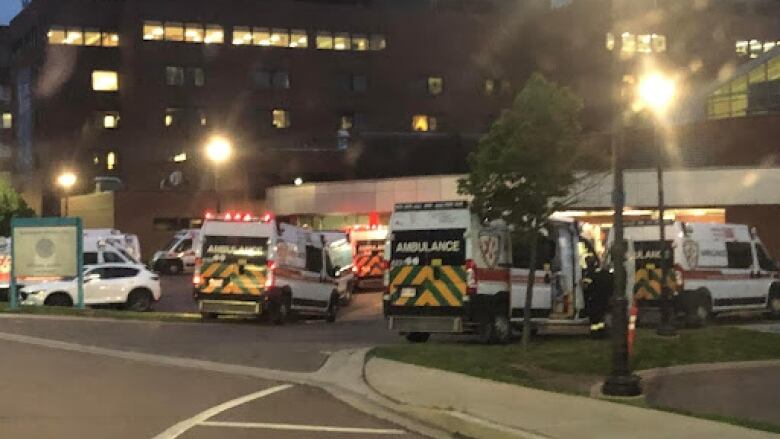 Multiple ambulances outside a multi-storey building in the dark.