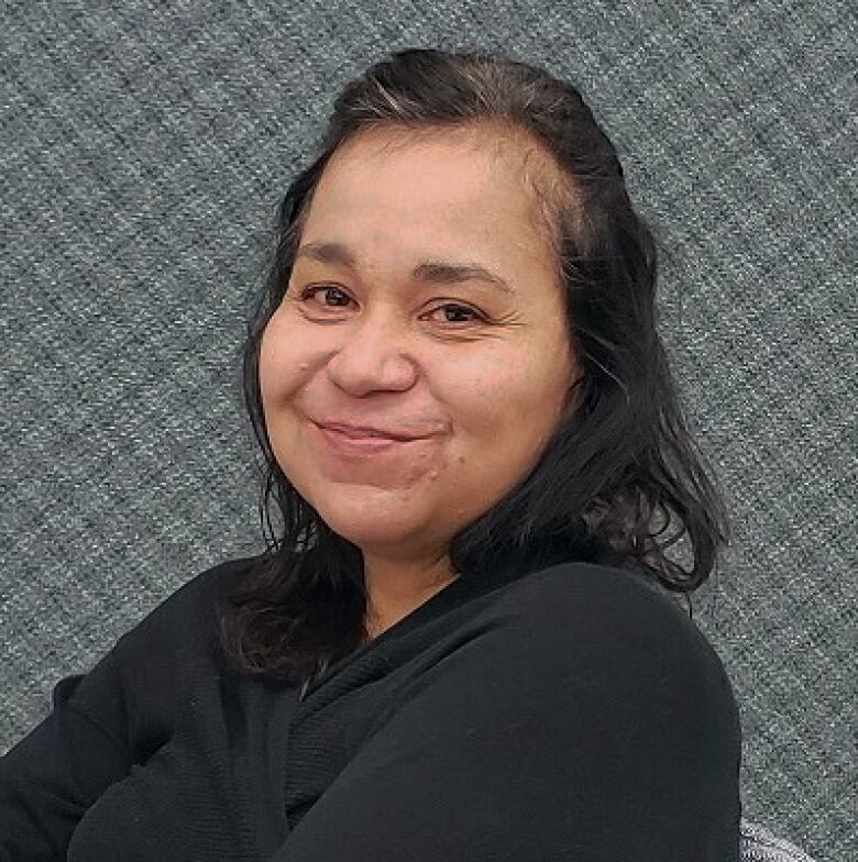 A missing person handout photo provided by RCMP shows a middle-aged Indigenous woman with grey streaks in her hair. She is wearing a black shirt and smiling at the camera.