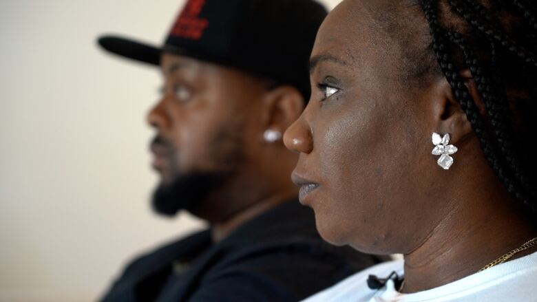 Jhody Batiste and Andre Henry are pictured in profile. Batiste is a Black woman wearing a silver earring. Henry is a Black man wearing a black hat.