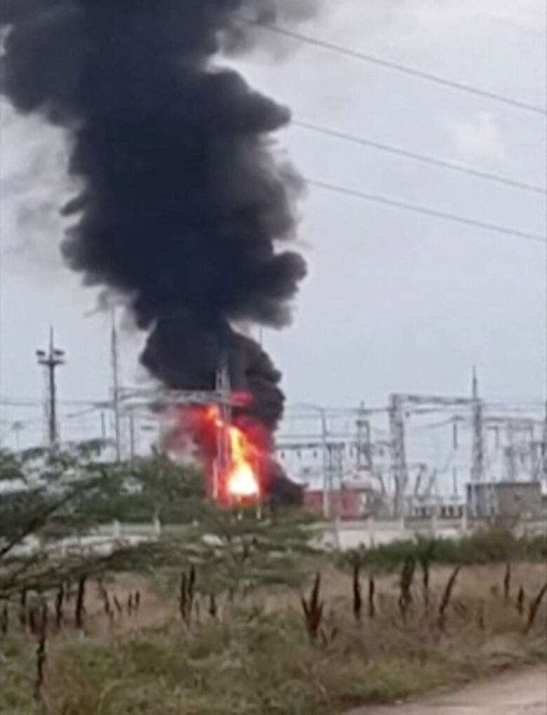 Black smoke rises from a fire seen near electrical towers.