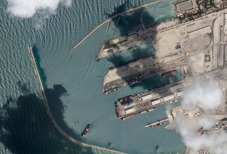 Aerial image of a ship in the water near concrete piers extending from the land. 