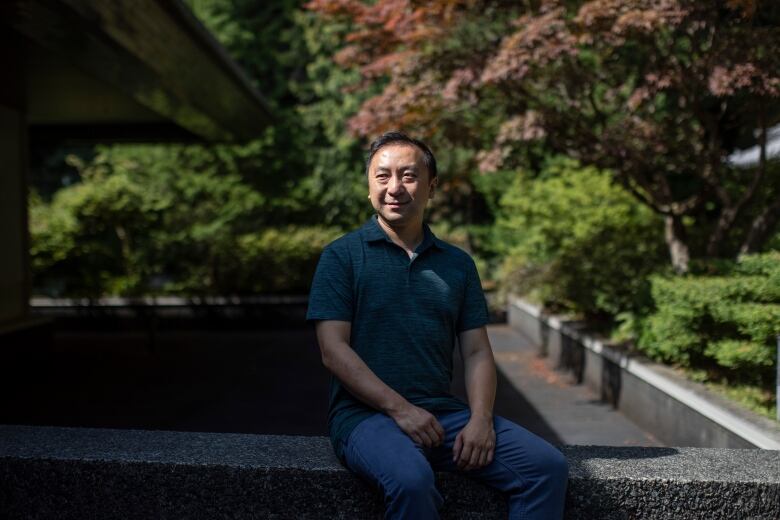 A man sits on a bench in a garden.