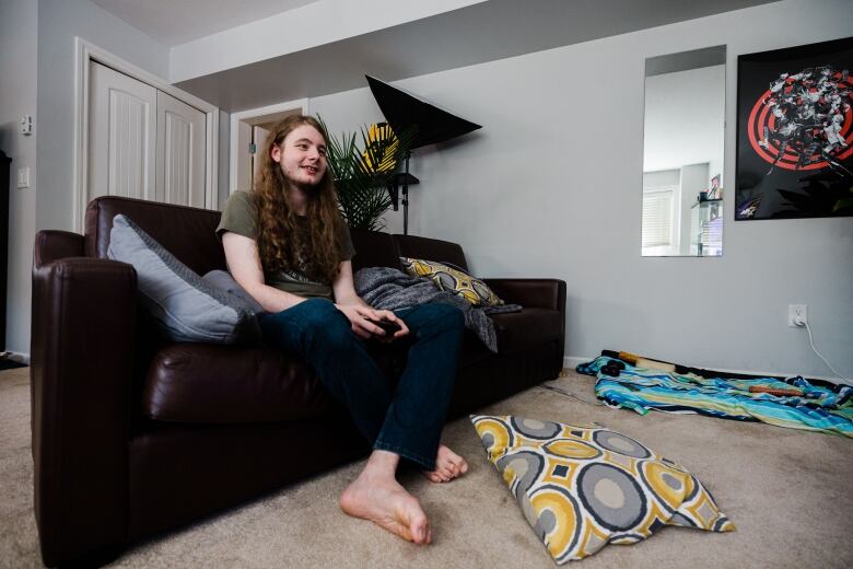 Jalen plays a game sitting on a black couch, with a yellow throw pillow on the carpeted floor.