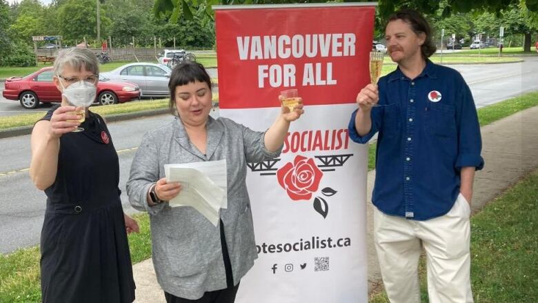 Two women and one man are pictured raising a toast next to a vertical banner with the text, 