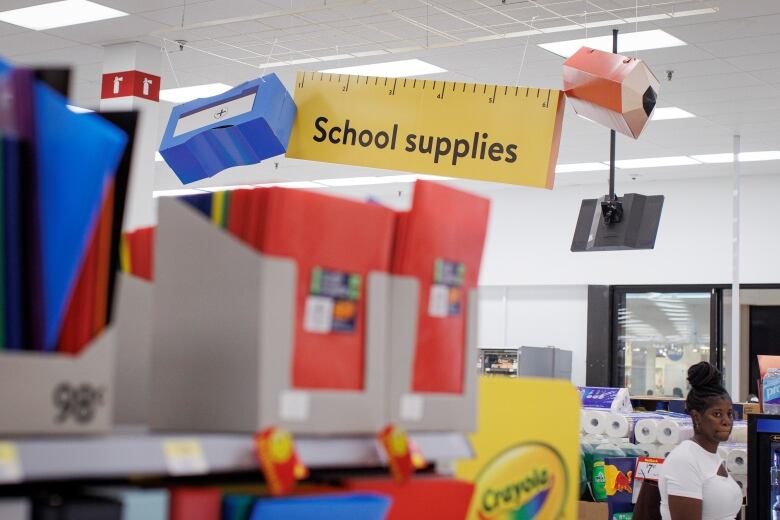 Overhead signage noting school supplies is seen above boxes containing binders, duotangs and other items.