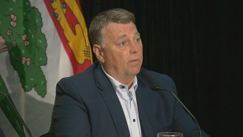 Dennis King, seated, with a P.E.I. flag behind him.