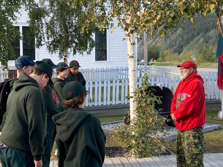 Man in a red Ranger sweater standing infront of a group of youth in green Ranger sweaters