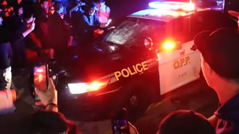 an OPP vehicle drives in a crowd with onlookers taking photos