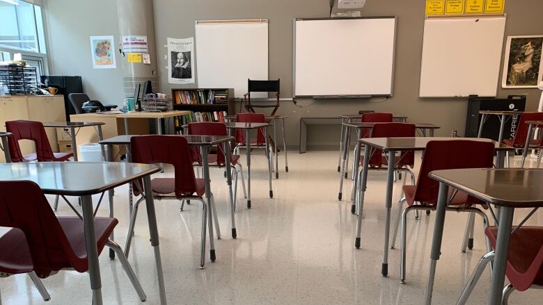 Desks and red plastic chairs in a classroom.