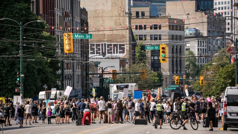 Dozens of people block off a large street during a protest.