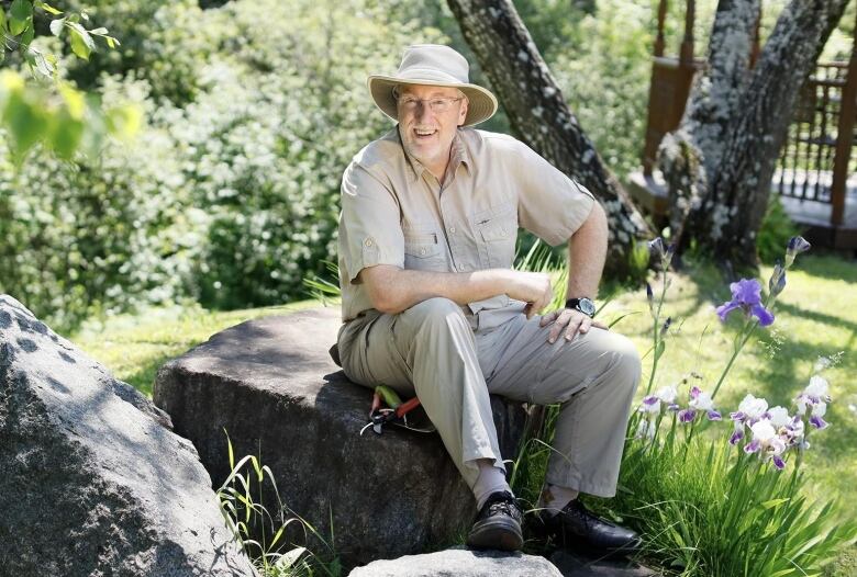 A man smiles while sitting on rocks.