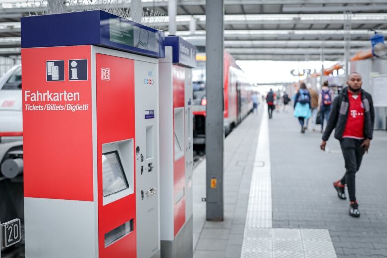 A man walks by a train ticket vending machine.