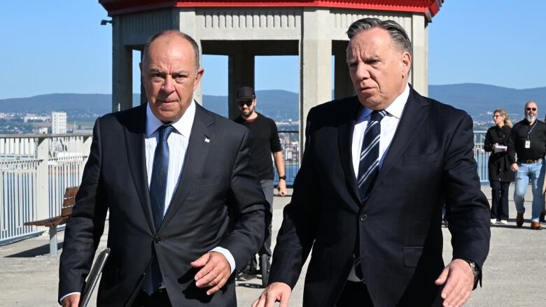 Two men in suits walk and talk.