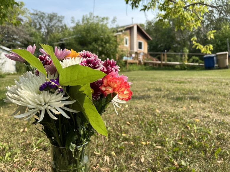 A closeup of a bouquet of flowers, placed on the yard of a house. 