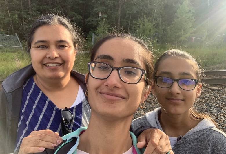 A smiling woman with her two school-aged daughters. 