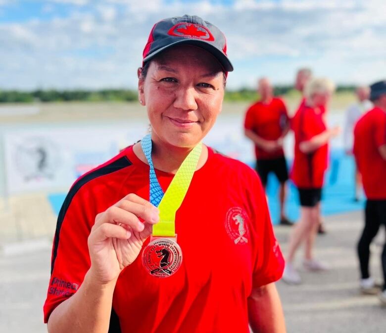 Smiling person holds a medal worn around her neck.