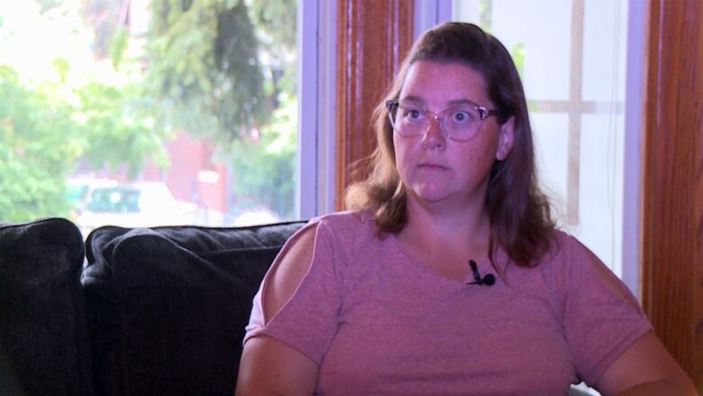 A woman wearing a pink t-shirt sitting on her couch