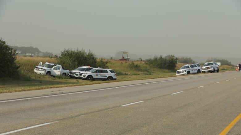 Police vehicles are seen on a stretch of Highway 11 near Rosthern, Sask., following the arrest of Myles Sanderson, on Sept. 7, 2022. The stolen Chevrolet Avalanche is seen on the left.