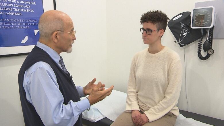 A doctor talks to a patient sitting on an examining table.