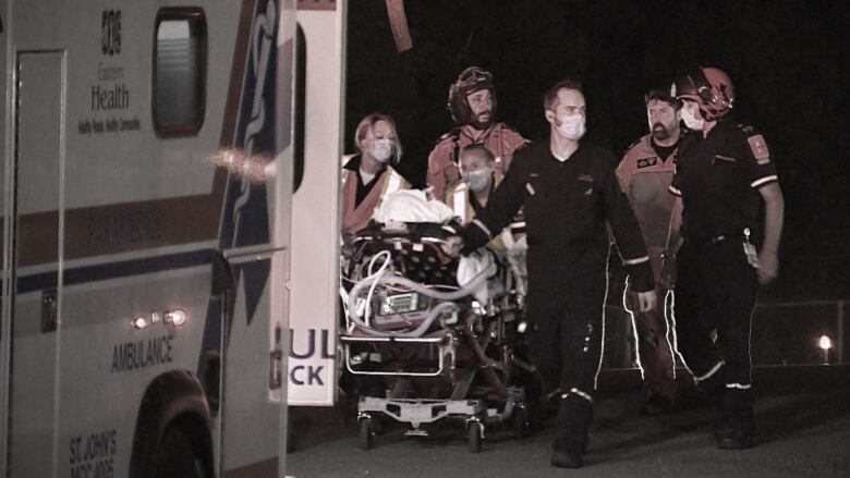 Paramedics wheel a stretcher carrying an injured worker.