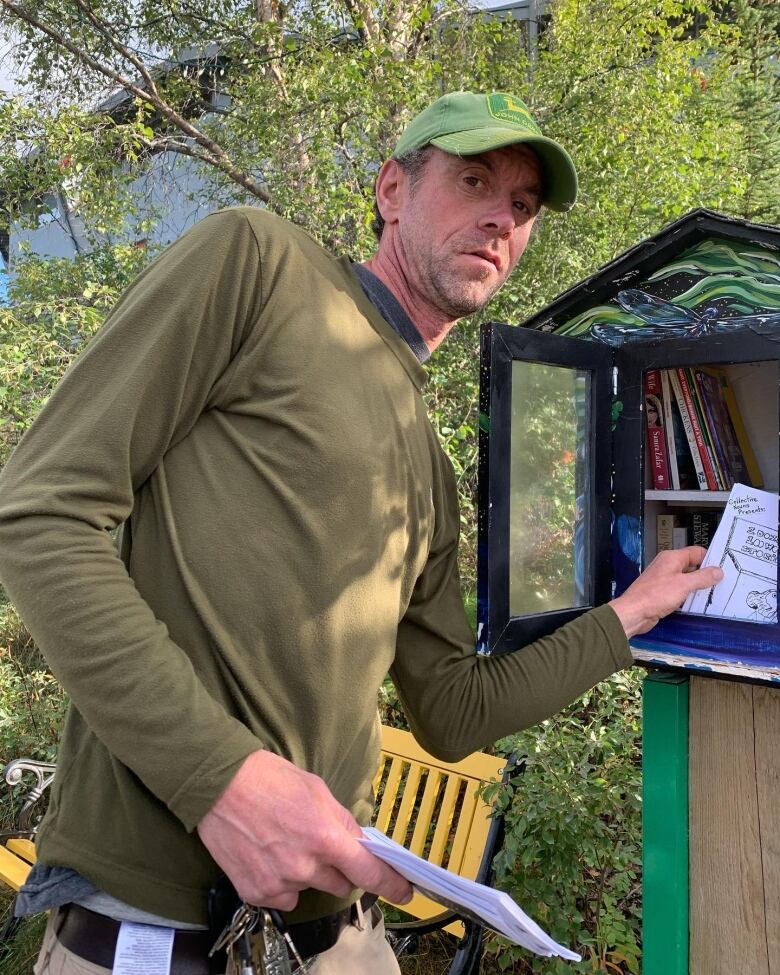 A portrait of a man placing a zine in a mini library.