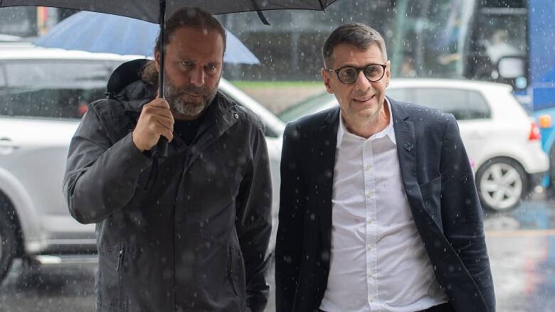 A man is holding an umbrella for someone else.