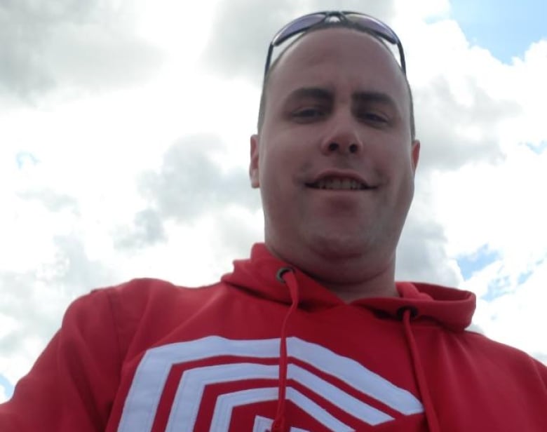 Photo shot from below of a man in sunglasses and red hoodie 