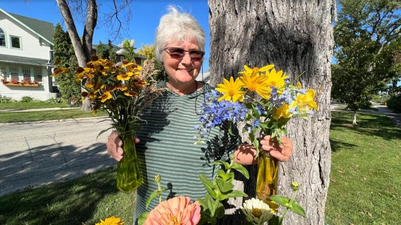 A woman in a green striped shirt holds colourful flower bouquets.