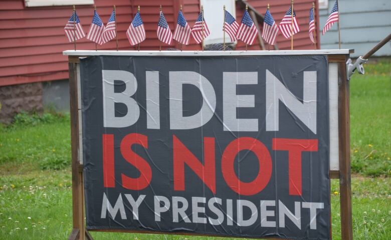 A sign on a lawn in Sault Ste. Marie, Michigan is adorned with American flags and reads 'Biden is not my president.'