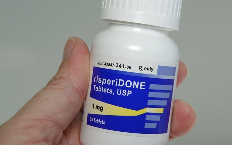 Hand holding a bottle of risperidone.