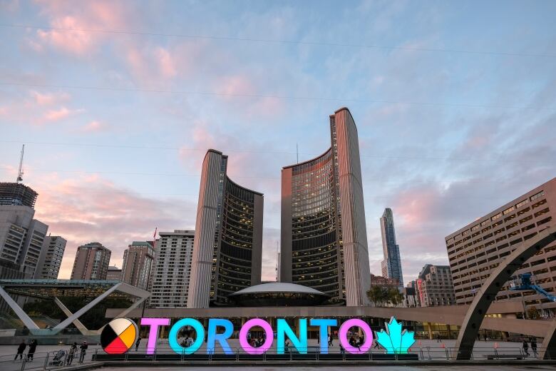 A sign says Toronto in front of the city hall building.