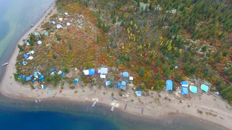 A birds-eye view of a camp set near the shores of a body of water.