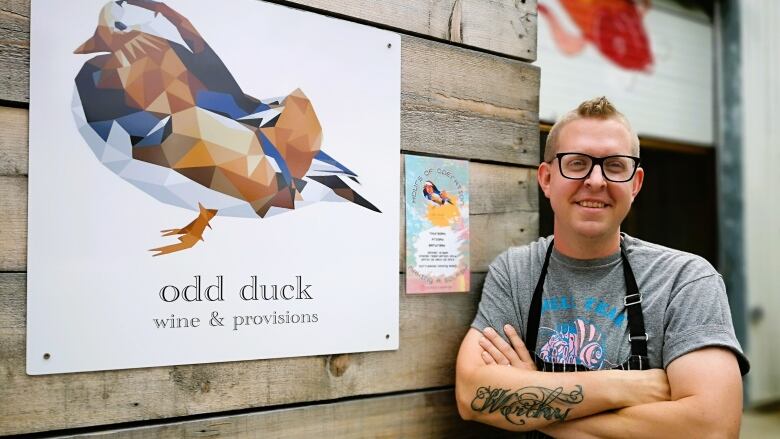 A local chef poses in front of his restaurant sign.