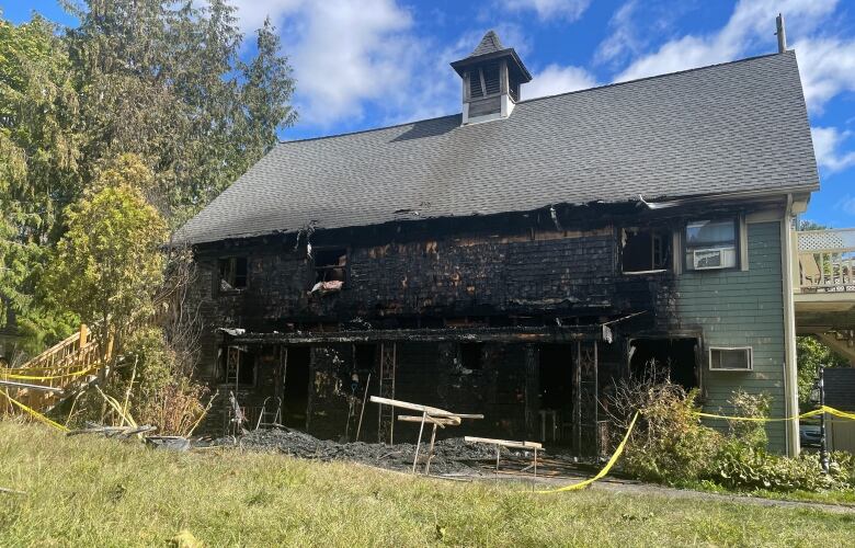 One wall of a wooden building is blackened by fire.