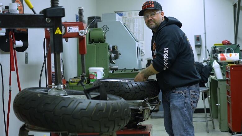 A man loads a tire onto a rig to remove it from the wheel. 