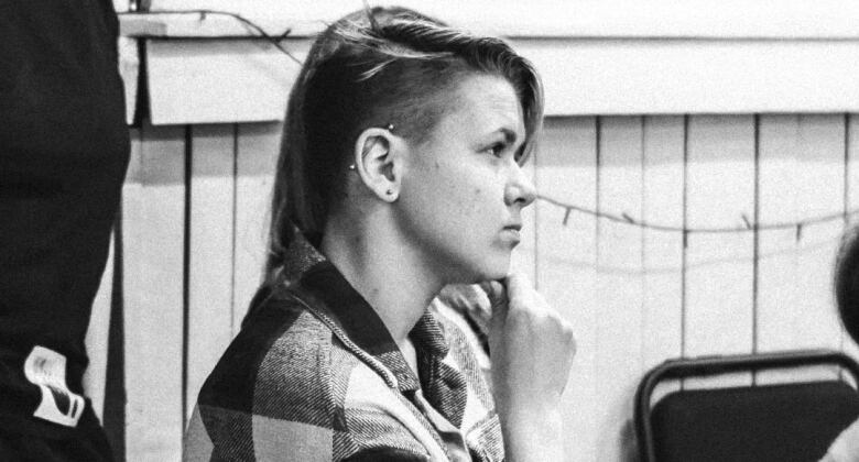 A black and white photo of a woman with her chin resting on her hand, looking sideways.