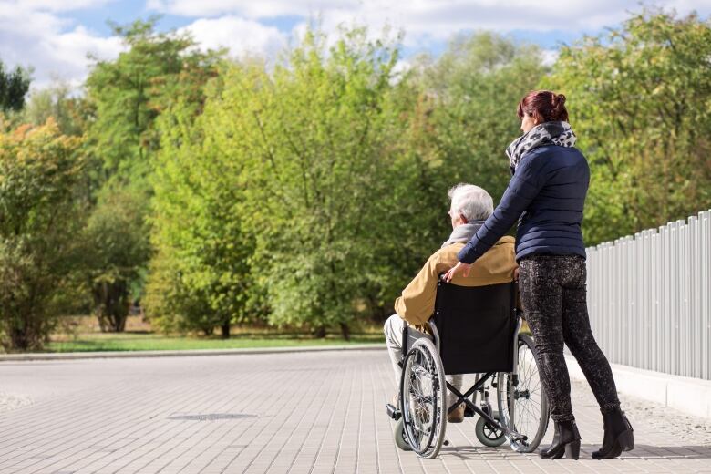 A person pushing another person in a wheelchair.