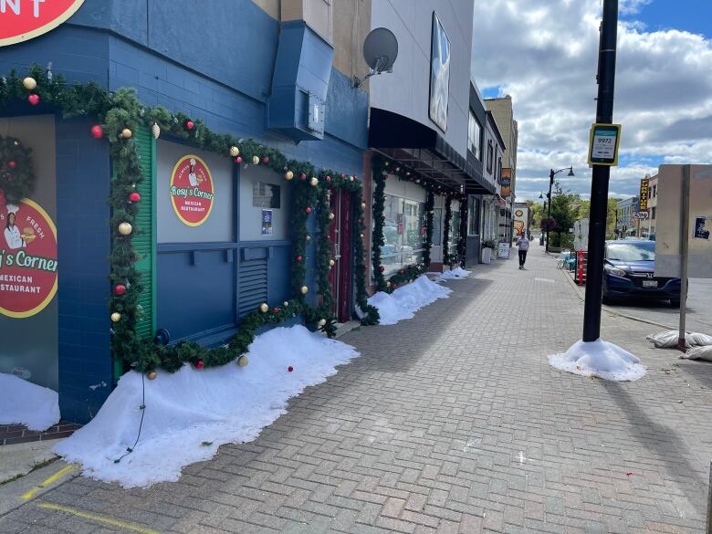 A downtown storefront with fake snow and Christmas decorations.