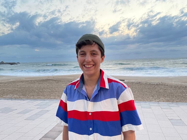 A young person poses for a photo in a toque and a striped shirt.