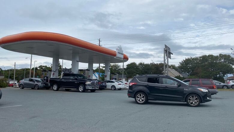 Cars lined up waiting to get to a gas pump.