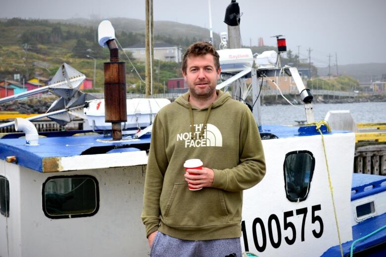 A man stands in front of a boat